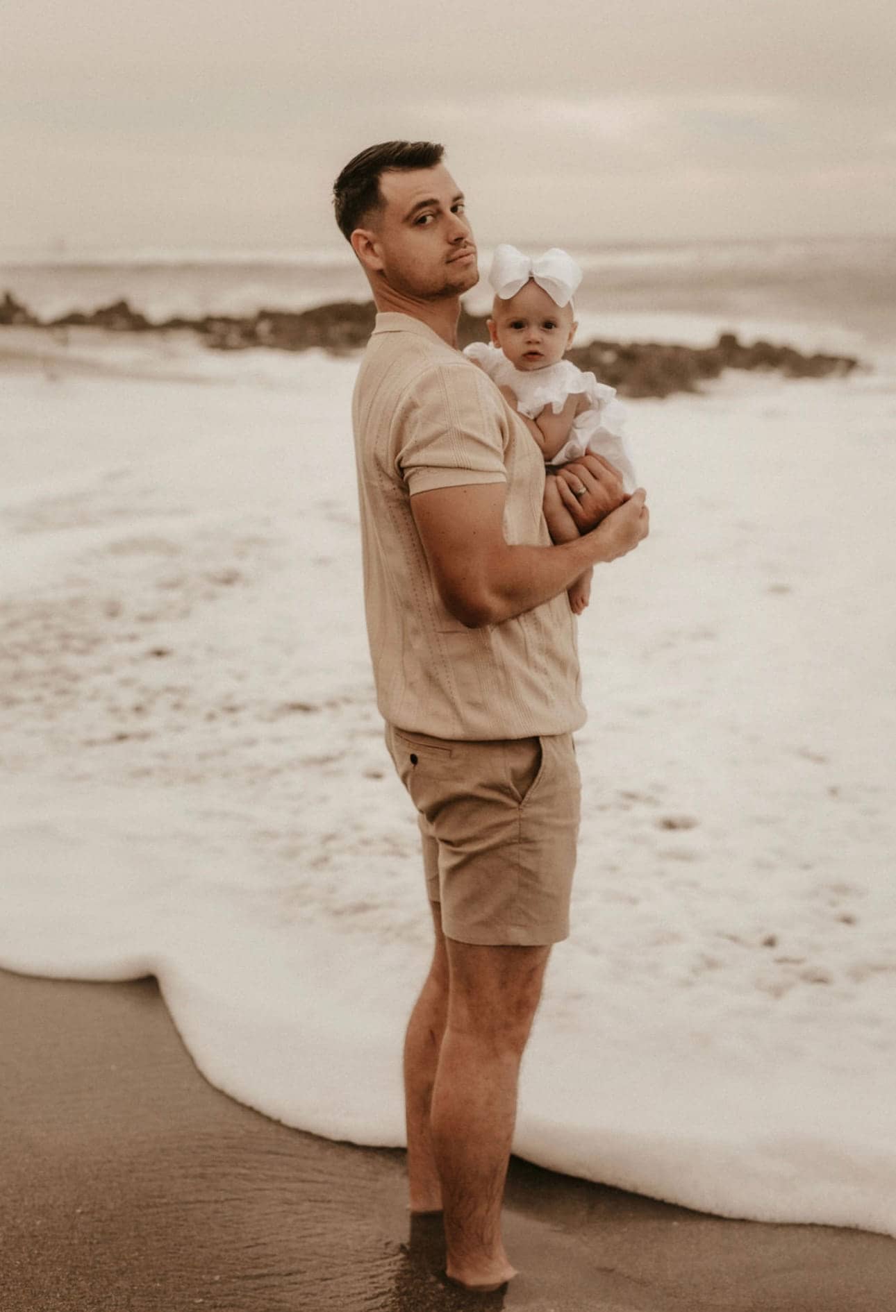 Christopher Molina holding his daughter at the shoreline